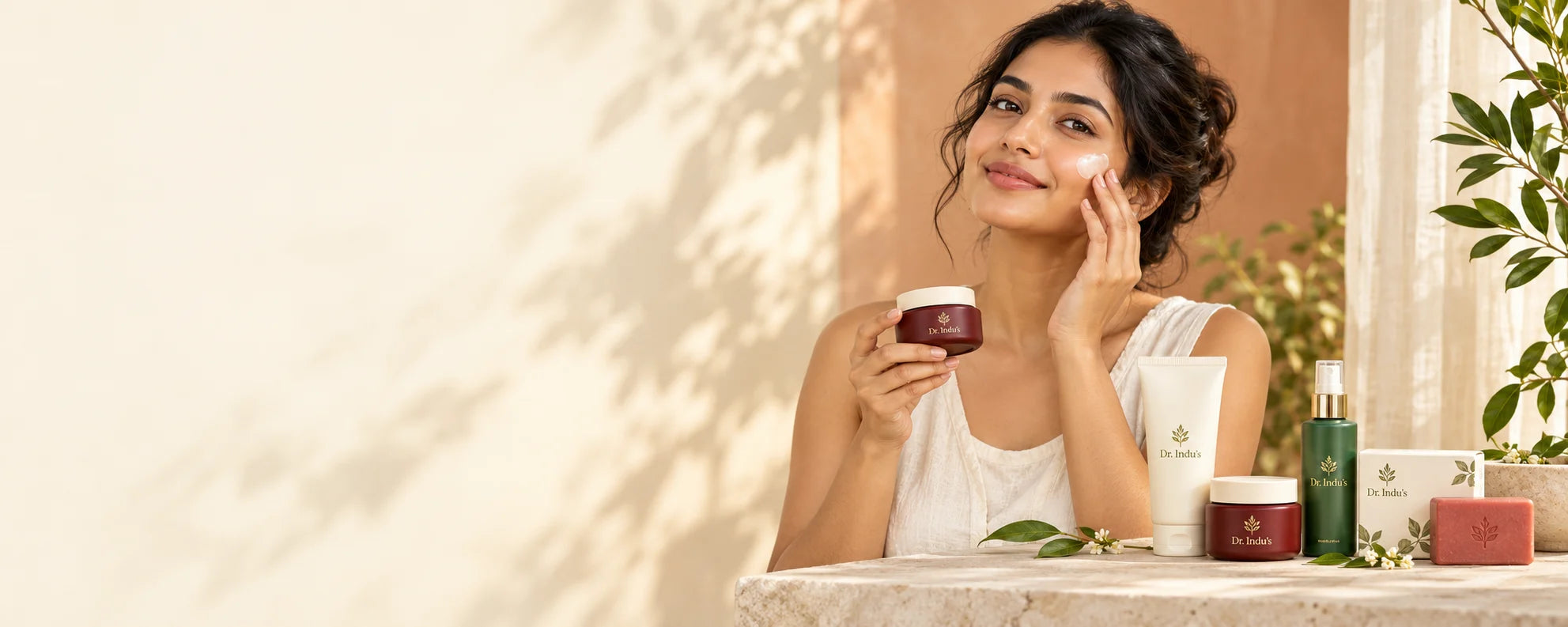 A woman using skincare in a warm botanical studio with concept product packaging